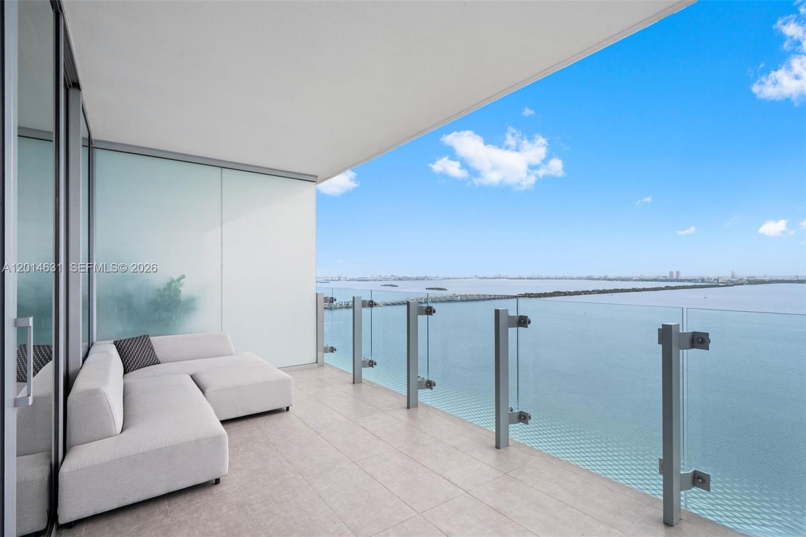 A balcony with a light-colored sectional sofa overlooks a large body of water — 700 NE 26th Ter # 2803, Miami FL 33137, MIAMI, FL