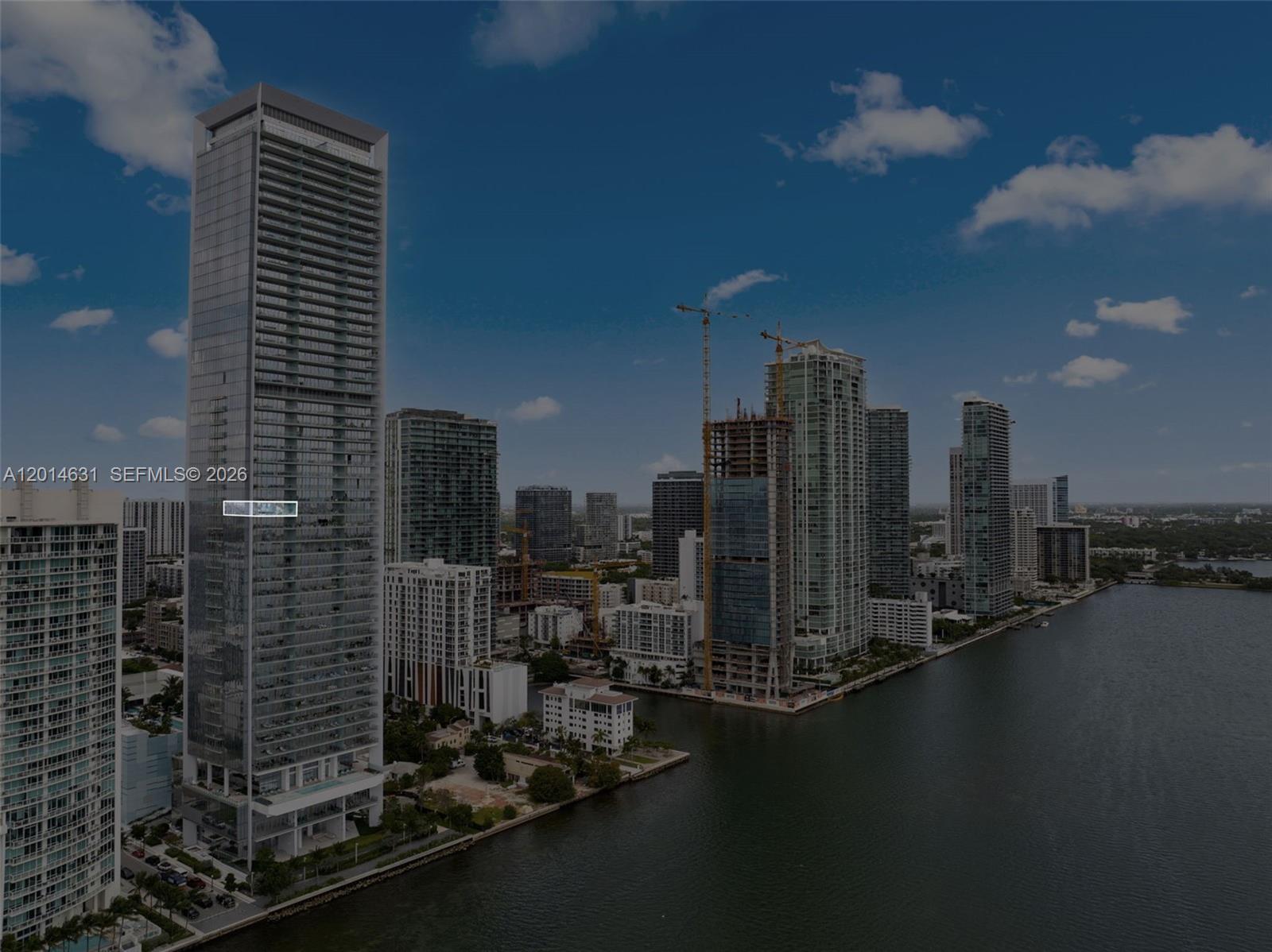An aerial view shows a tall glass skyscraper overlooking a waterfront in a city — 700 NE 26th Ter # 2803, Miami FL 33137, MIAMI, FL