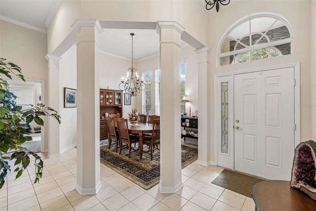 A foyer with tile flooring leads to a dining room framed by two white columns — 7308 AMBLESIDE DRIVE, LAND O LAKES, FL
