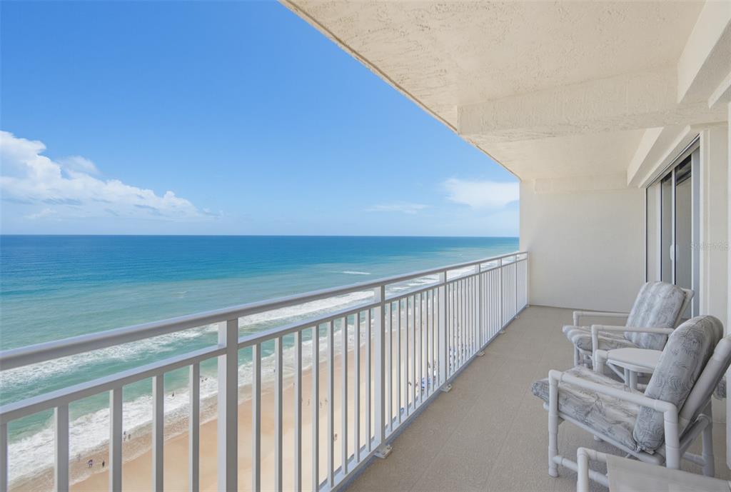 A balcony with white railings overlooks the ocean and beach with two chairs — 2545 S ATLANTIC AVENUE UNIT 1804, DAYTONA BEACH SHORES, FL