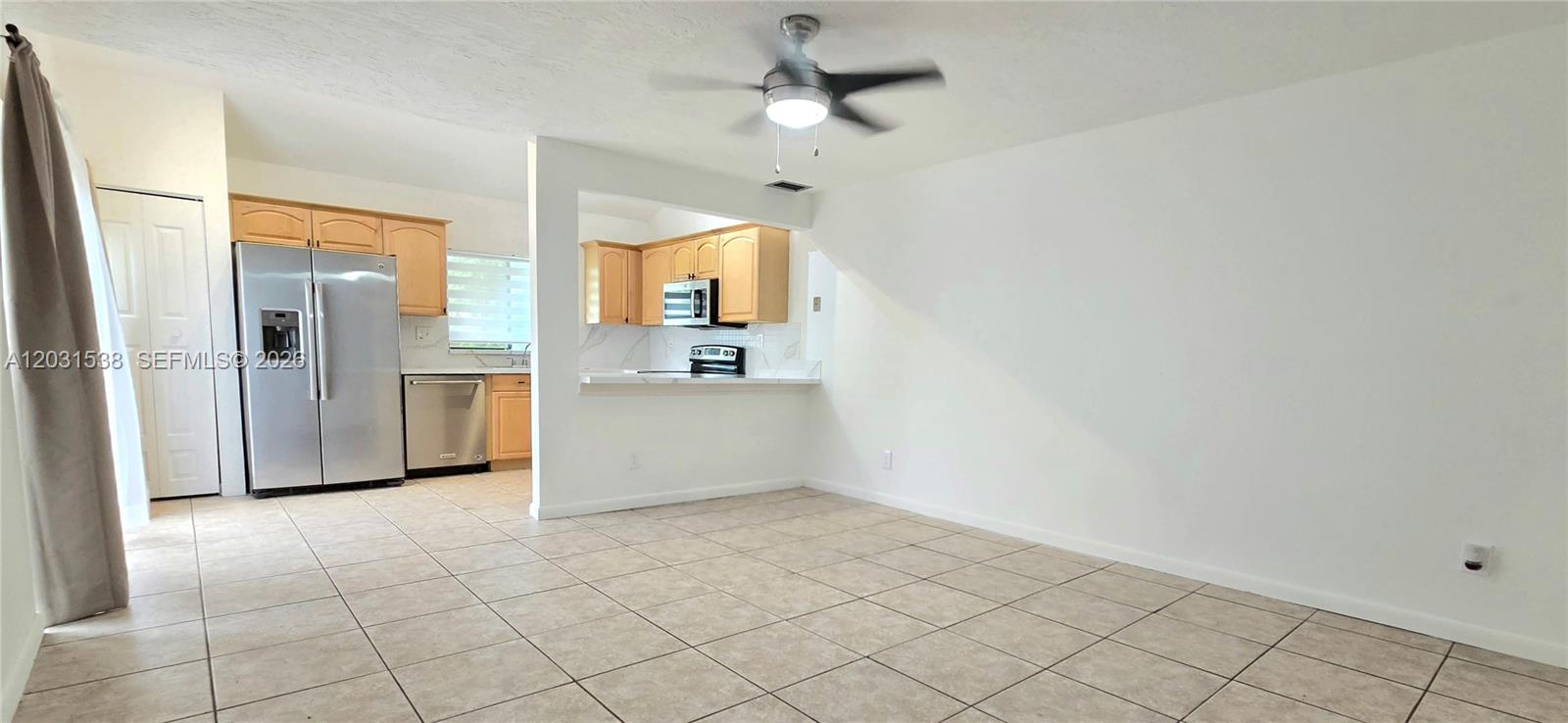 A kitchen with light wood cabinets and stainless steel appliances opens to a tiled room — 608 Commodore Dr, Plantation FL 33325, PLANTATION, FL