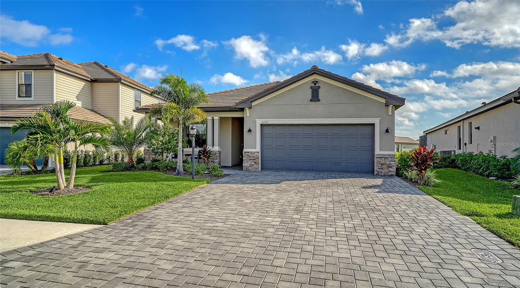 A single-story house with a gray garage, stone accents, and a paved driveway — 5225 BLUE CRUSH, BRADENTON, FL