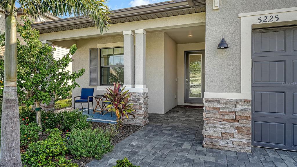 A paved walkway leads to the front entrance of a house with stone accents — 5225 BLUE CRUSH, BRADENTON, FL