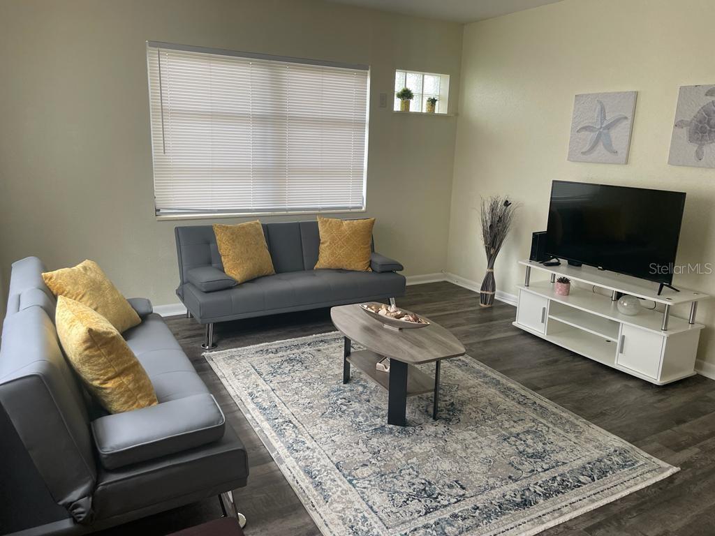 A living room features two gray futons, a coffee table, and a white media console — 25 6TH AVENUE SE, LARGO, FL