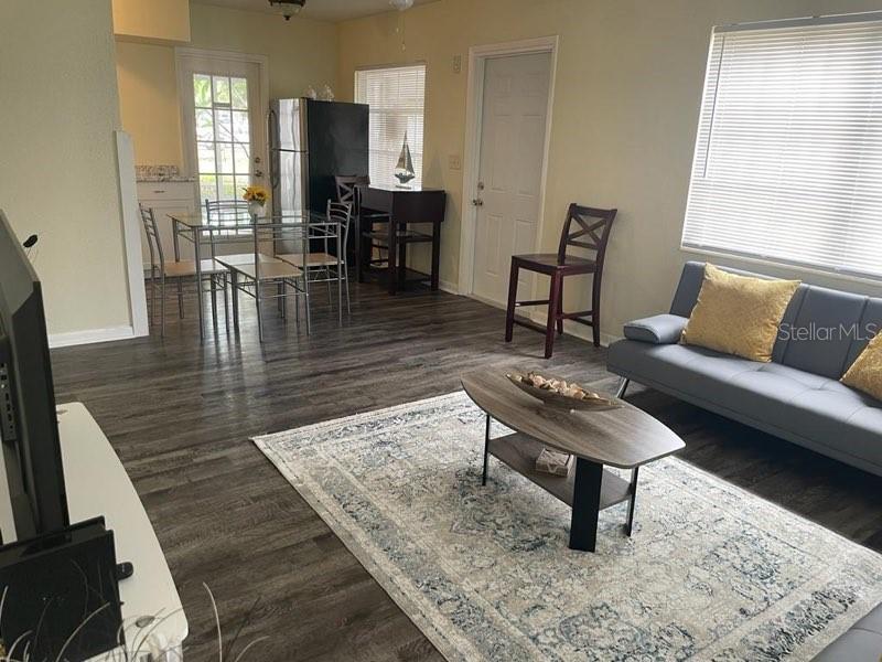 A living room and dining area feature wood-look flooring, a gray sofa, and a rug — 25 6TH AVENUE SE, LARGO, FL