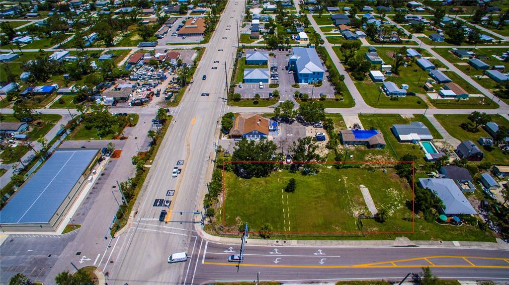An aerial view shows a vacant, rectangular grass lot outlined in red next to a road — 2931 PLACIDA ROAD, ENGLEWOOD, FL