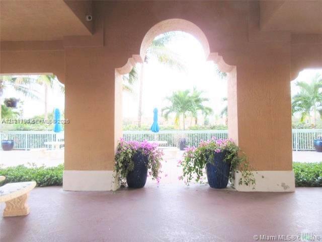 A covered patio features arched openings, potted flowers, and a view of palm trees — 6500 NW 114th Ave # 1021, Doral FL 33178, DORAL, FL