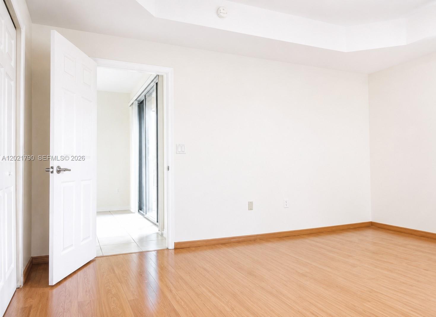 An empty room with light wood flooring, white walls, and an open doorway — 6500 NW 114th Ave # 1021, Doral FL 33178, DORAL, FL