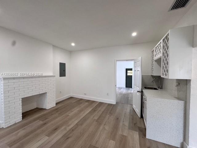 A room features a white brick fireplace, wood-look flooring, and a small kitchenette area — 4783 NW Flagler Ter, Miami FL 33126, MIAMI, FL
