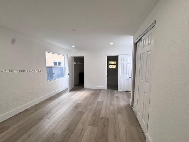 A bedroom with white walls, light wood-look flooring, and a white sliding closet door — 4783 NW Flagler Ter, Miami FL 33126, MIAMI, FL