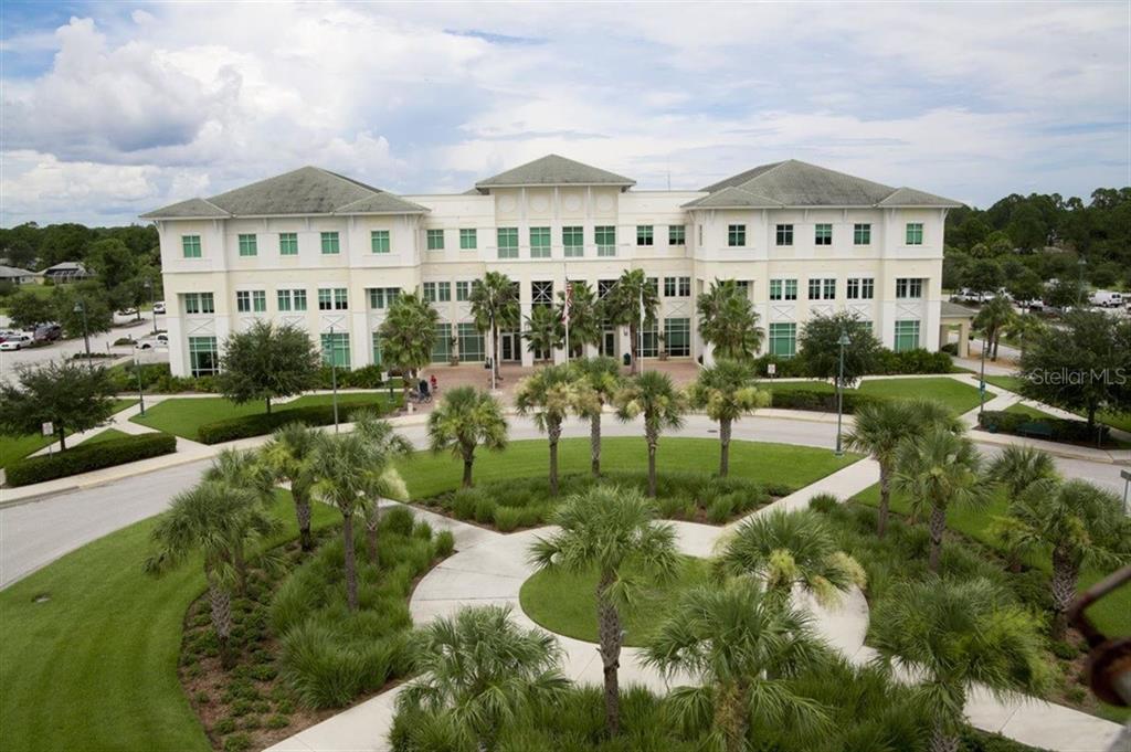 An aerial view of a three-story commercial building with a landscaped courtyard and palm trees — EMPORIA TERRACE, NORTH PORT, FL