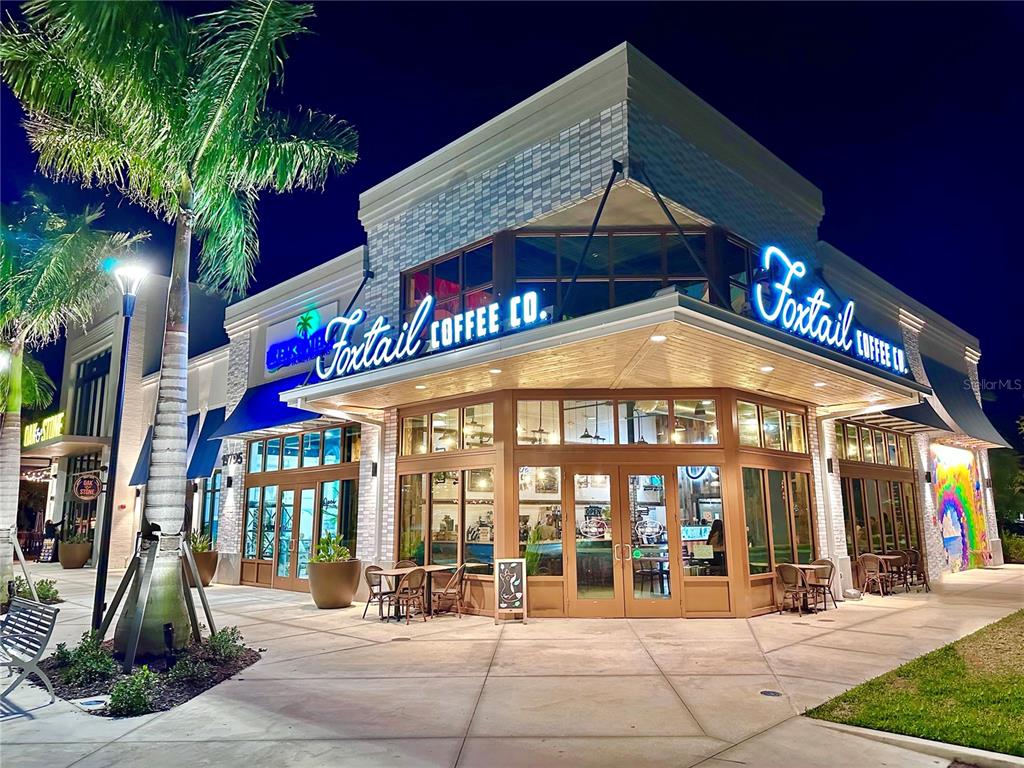 A corner view of a Foxtail Coffee Co. storefront at night with outdoor seating — EMPORIA TERRACE, NORTH PORT, FL