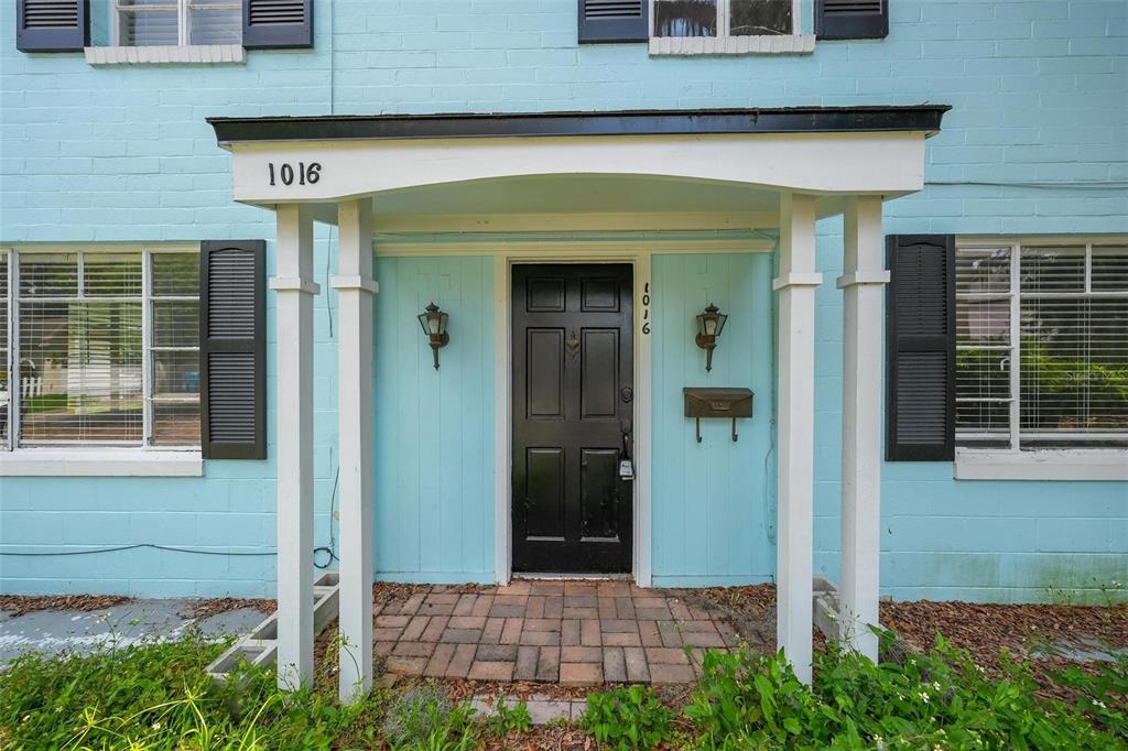 A light blue house exterior features a black front door under a covered entryway — 1016 ATKINS PLACE, ORLANDO, FL