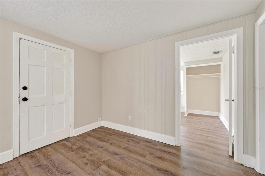 An interior room with wood-look flooring, a white door, and a doorway leading to another room — 1016 ATKINS PLACE, ORLANDO, FL