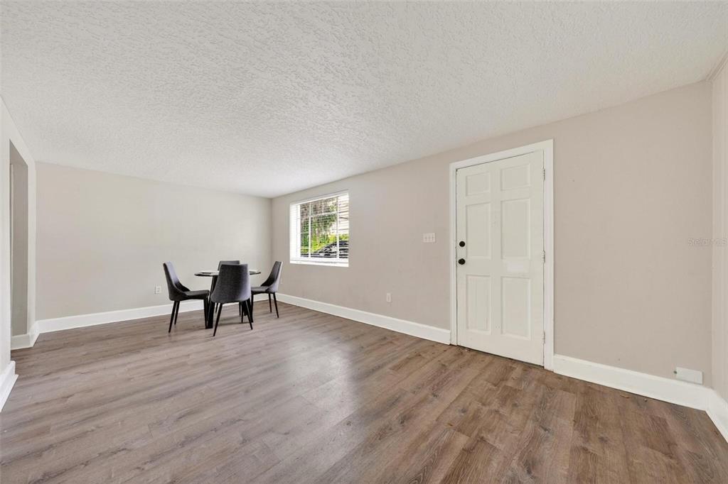 A dining area with wood-look flooring, a small table with four chairs, and a white door — 1016 ATKINS PLACE, ORLANDO, FL