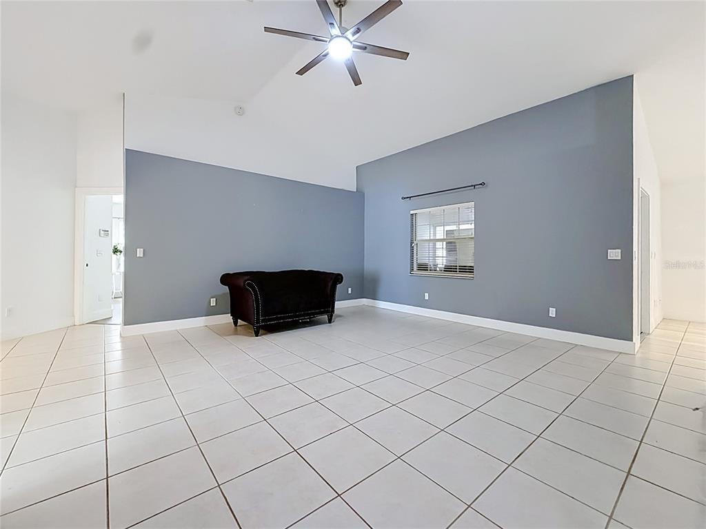 A living room features gray walls, white tile flooring, a vaulted ceiling, and a sofa — 13850 SW 71ST LANE, OCALA, FL