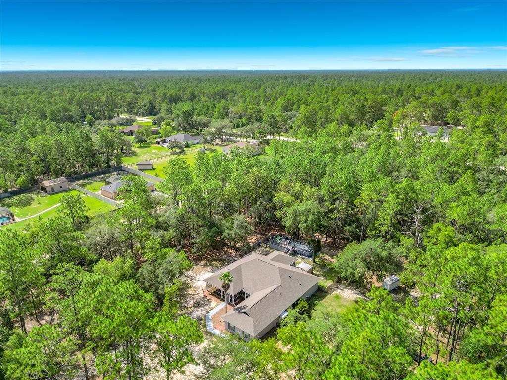 An aerial view shows a house with a pool surrounded by dense forest and trees — 13850 SW 71ST LANE, OCALA, FL