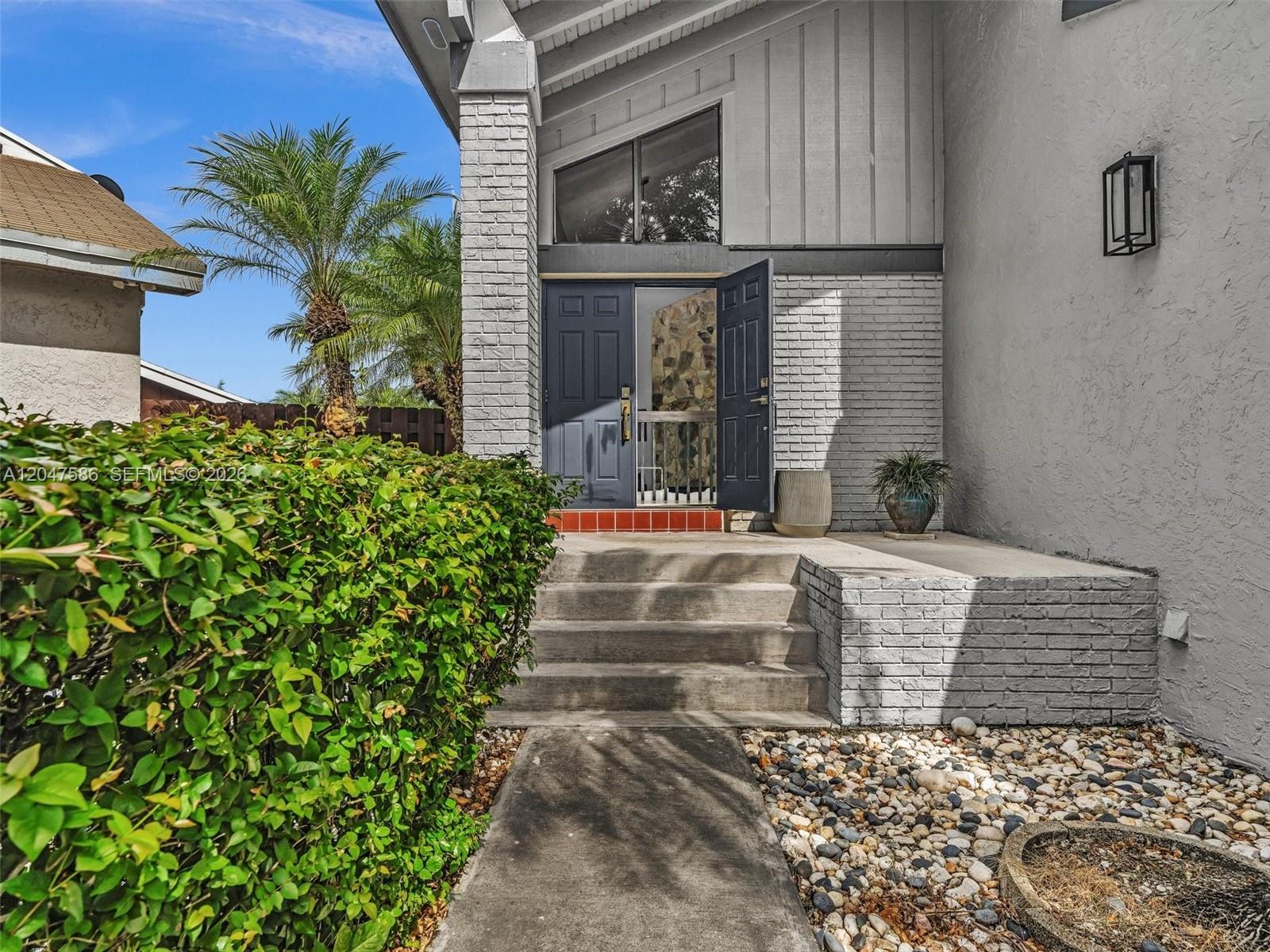 A concrete walkway leads to the front entrance of a house with gray brick accents — 4224 SW 148th Pl, Miami FL 33185, MIAMI, FL