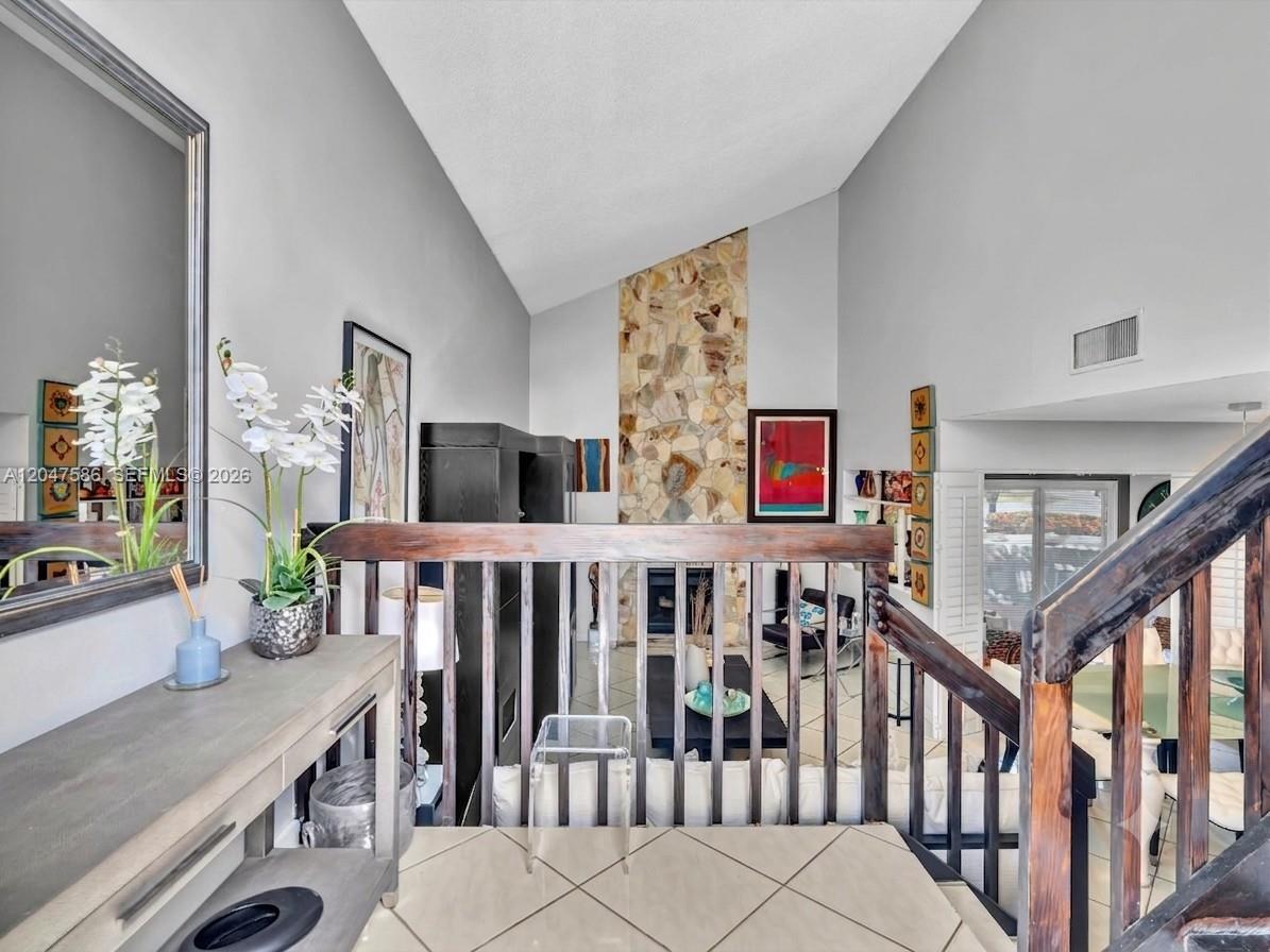 A view from a landing overlooking a living room with a stone fireplace and stairs — 4224 SW 148th Pl, Miami FL 33185, MIAMI, FL