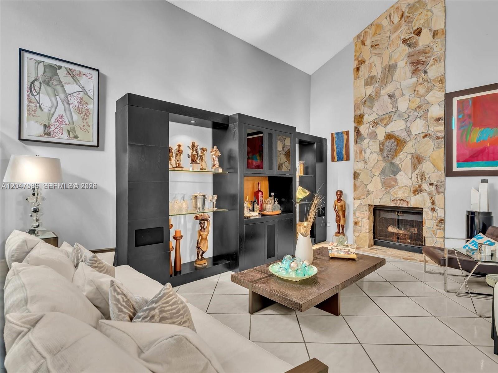 A living room features a stone fireplace, a large black shelving unit, and tile flooring — 4224 SW 148th Pl, Miami FL 33185, MIAMI, FL