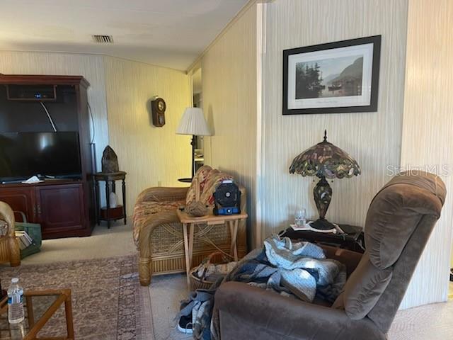 A living room features a television console, a wicker chair, and a recliner — 19 BOBCAT TRAIL, WILDWOOD, FL