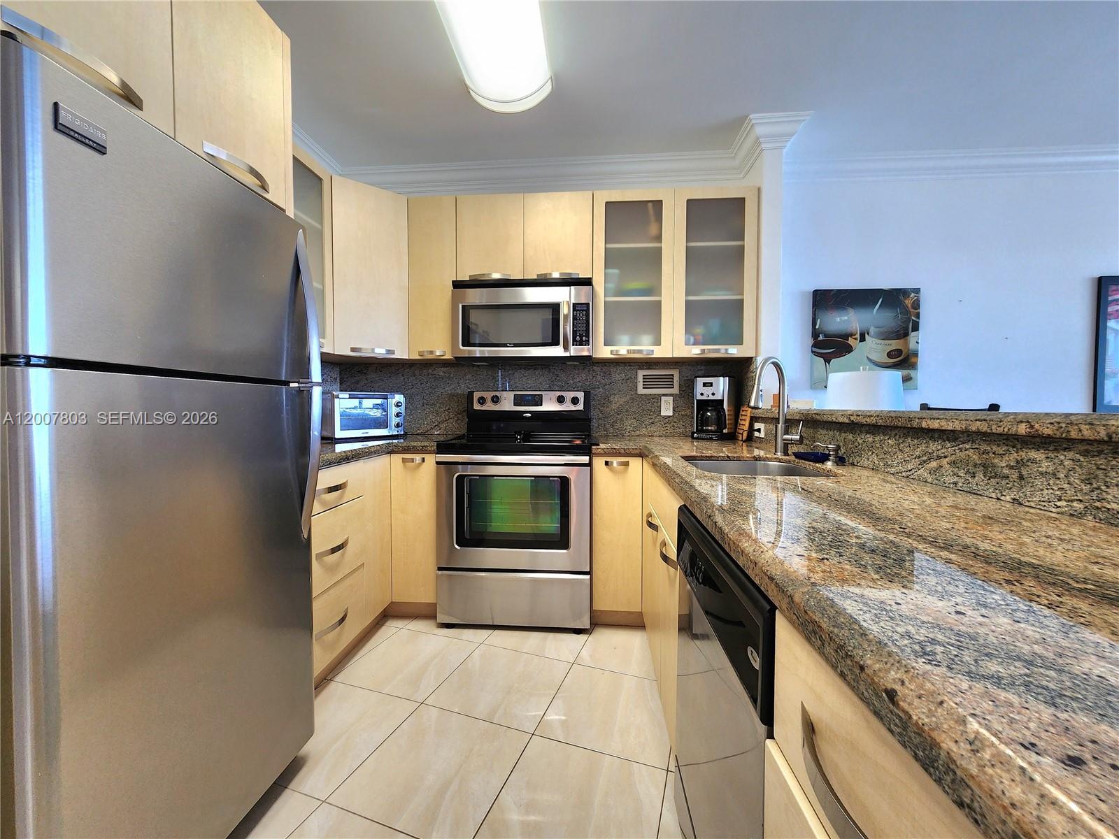 A kitchen features stainless steel appliances, light wood cabinets, and granite countertops — 3505 S Ocean Dr # 1103, Hollywood FL 33019, HOLLYWOOD, FL