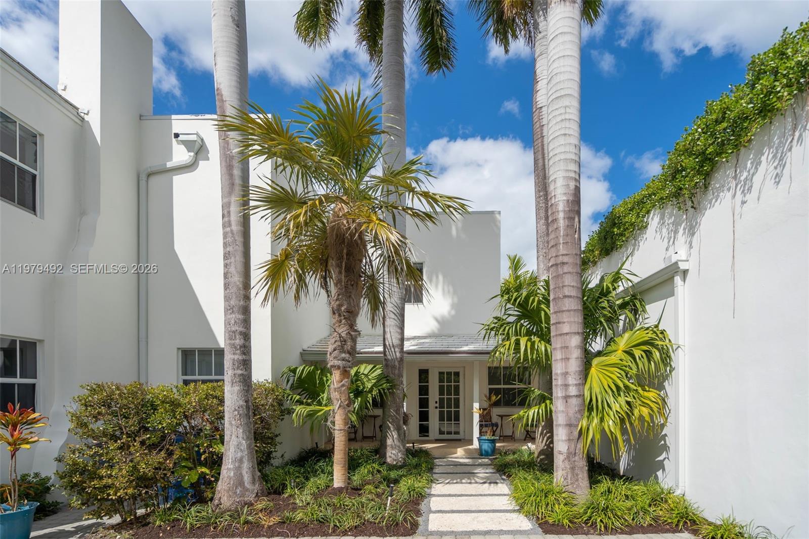 A white house exterior features a stone walkway leading to a glass-paned front door — 707 W 54th St, Miami Beach FL 33140, MIAMI BEACH, FL