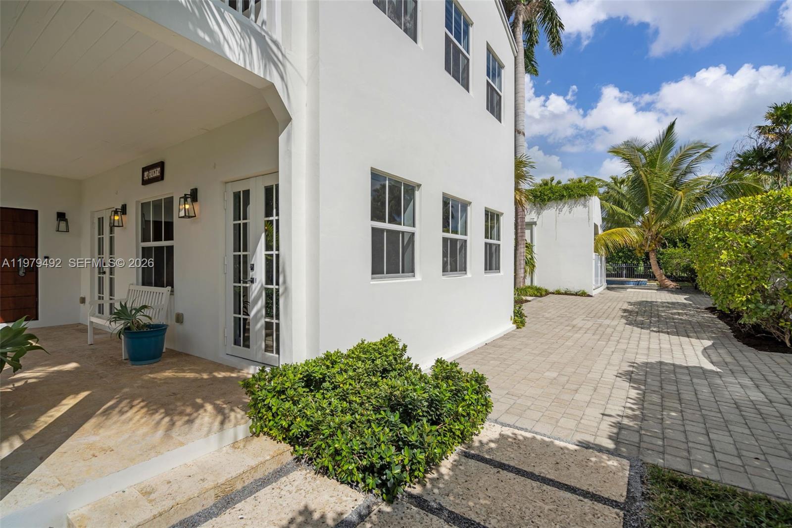 A white exterior building features a covered patio, glass-paned doors, and a paved walkway — 707 W 54th St, Miami Beach FL 33140, MIAMI BEACH, FL