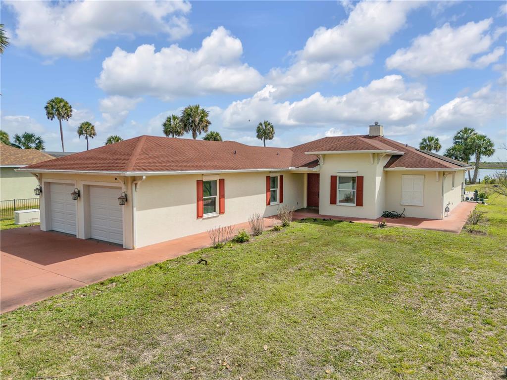A single-story house with a two-car garage, red roof, and light-colored stucco exterior — 2185 TURNBULL BAY ROAD, NEW SMYRNA BEACH, FL