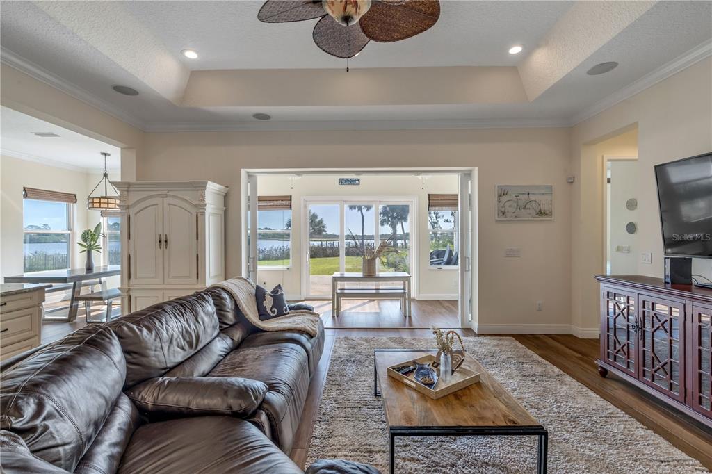 A living room with a leather sofa, tray ceiling, and sliding doors opening to a view — 2185 TURNBULL BAY ROAD, NEW SMYRNA BEACH, FL