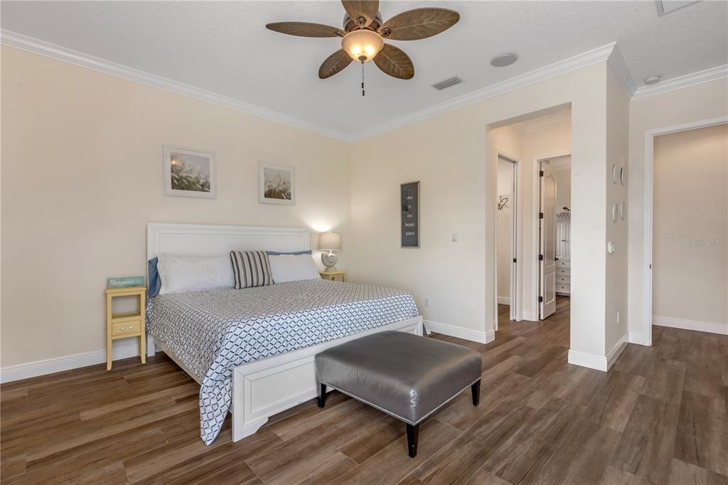 A bedroom features a white bed frame, a grey ottoman, and wood-look tile flooring — 2185 TURNBULL BAY ROAD, NEW SMYRNA BEACH, FL