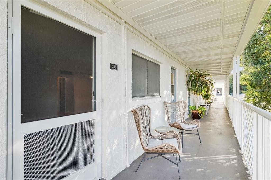 An outdoor walkway features a white door labeled 213, two wicker chairs, and a railing — 320 LAKEVIEW STREET UNIT 213, ORLANDO, FL