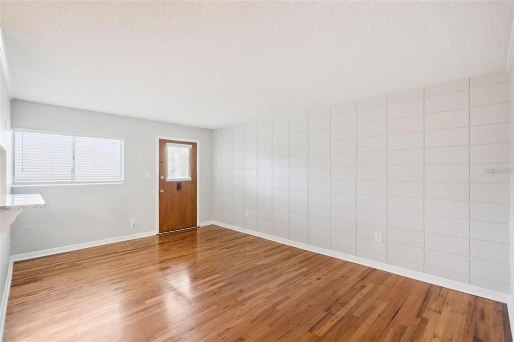 An empty room features hardwood floors, a window with blinds, and a grid-patterned accent wall — 320 LAKEVIEW STREET UNIT 213, ORLANDO, FL