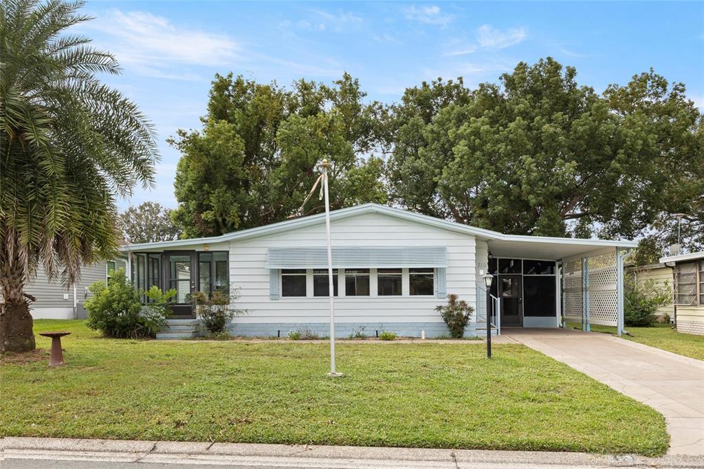 A single-story house with white siding, a carport, and a screened-in porch — 712 JASON DRIVE, LADY LAKE, FL