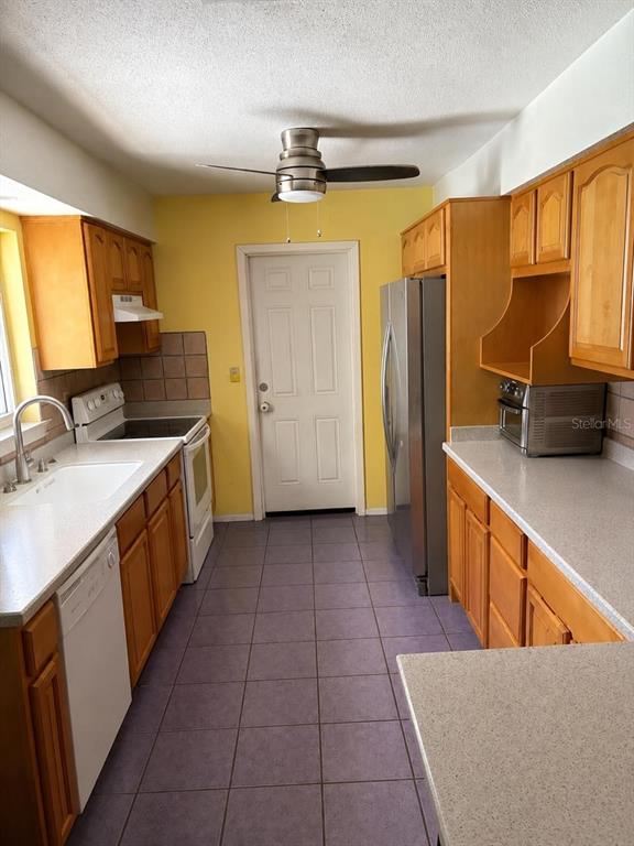 A kitchen with wood cabinets, stainless steel appliances, yellow walls, and purple tile flooring — 2571 CENTRAL AVENUE, CLEARWATER, FL