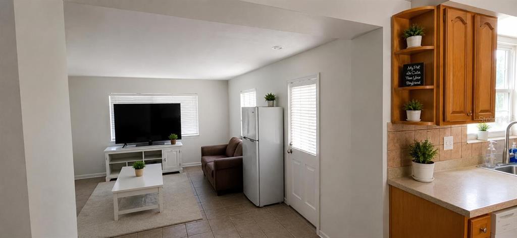 A living room with a television and sofa connects to a kitchen with wooden cabinets — 2571 CENTRAL AVENUE, CLEARWATER, FL
