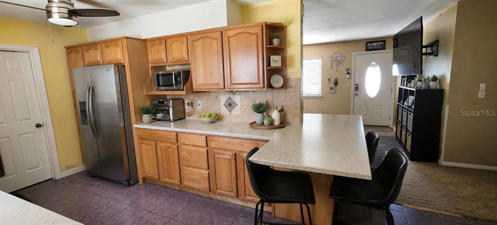 A kitchen features light wood cabinets, stainless steel appliances, a breakfast bar, and tile flooring — 2571 CENTRAL AVENUE, CLEARWATER, FL