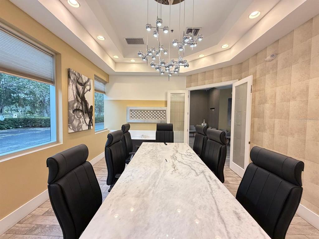 A conference room features a long marble table, black leather chairs, and a modern chandelier — 7901 KINGSPOINTE PARKWAY UNIT 16 and 17, ORLANDO, FL