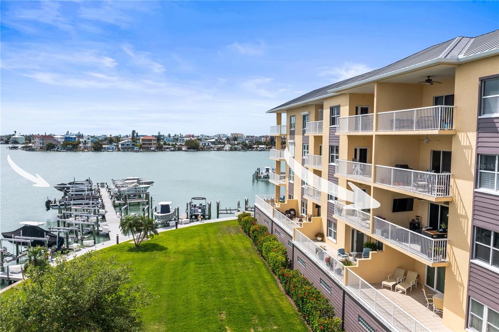 An exterior view of a multi-story apartment building overlooking a boat dock and water — 425 150TH AVENUE UNIT 2303, MADEIRA BEACH, FL