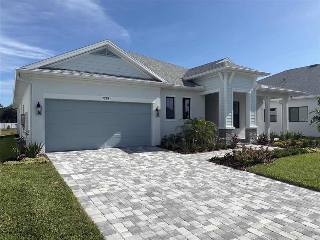 A single-story house with a light blue exterior, a two-car garage, and a paved driveway — 7249 MEADOWSHADE COURT, SARASOTA, FL