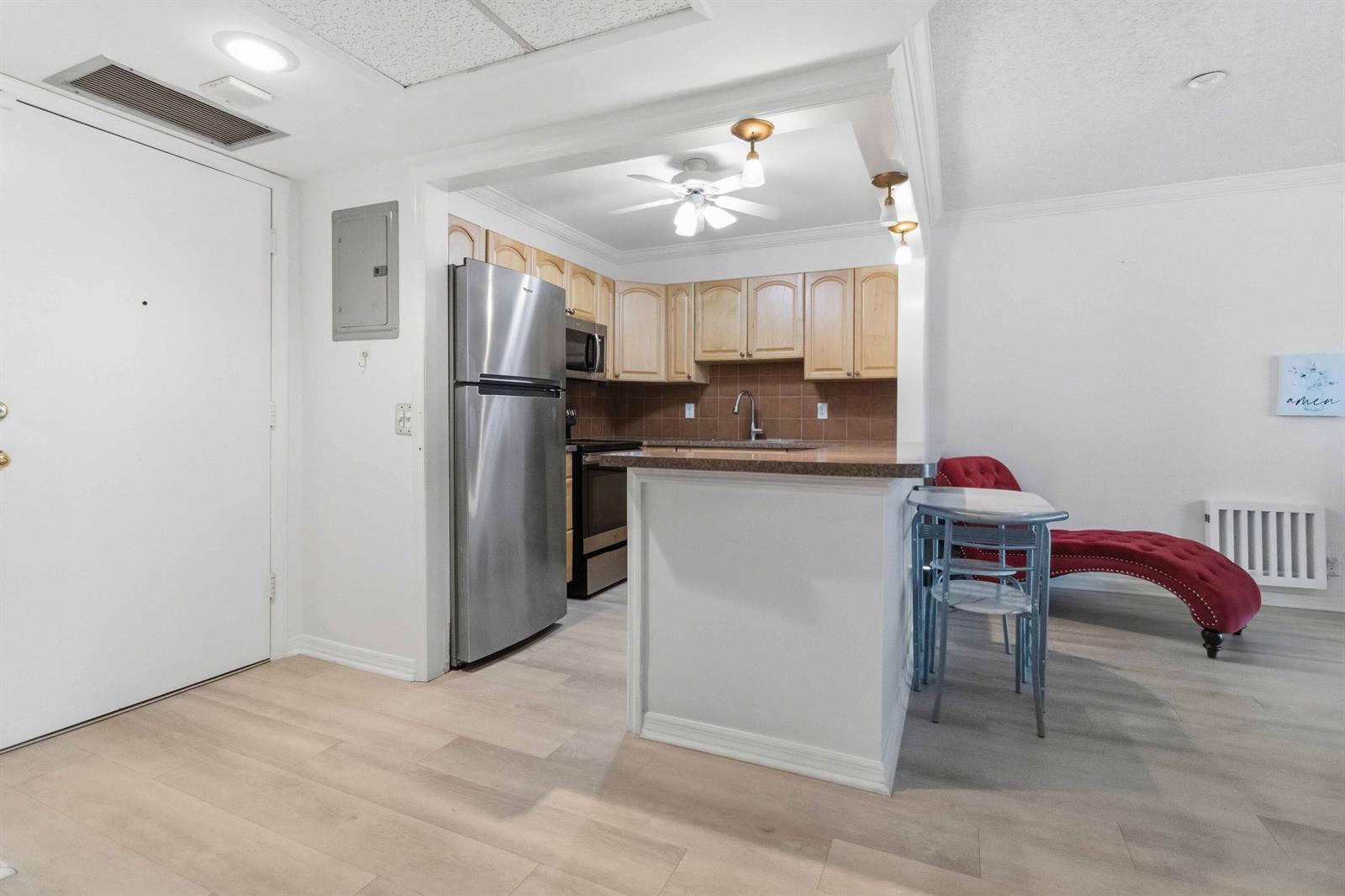 A kitchen with light wood cabinets, stainless steel appliances, and a breakfast bar — 259 S Cypress Road # 506, Pompano Beach FL 33060, POMPANO BEACH, FL