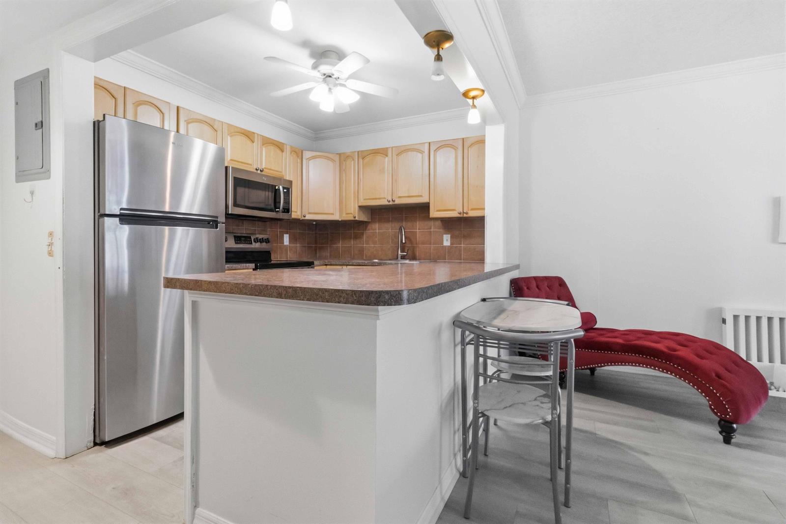 A kitchen with light wood cabinets, stainless steel appliances, and a breakfast bar peninsula — 259 S Cypress Road # 506, Pompano Beach FL 33060, POMPANO BEACH, FL