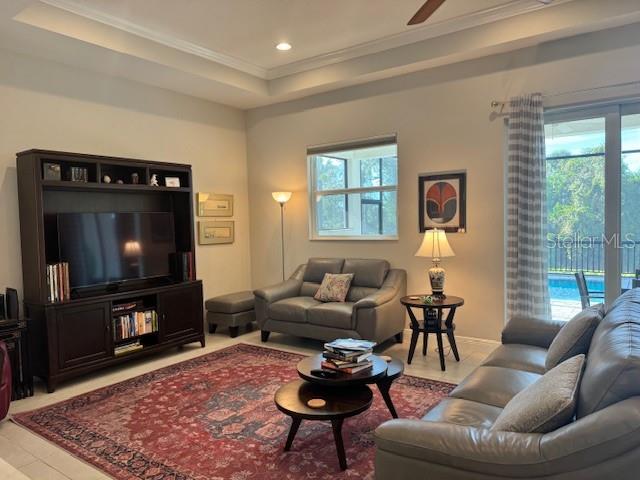 A living room features a large entertainment center, gray leather furniture, and a patterned rug — 6224 CHAMPIONS ROW STREET, BRADENTON, FL