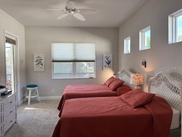 A bedroom features two beds with red bedding, a ceiling fan, and white wicker furniture — 6224 CHAMPIONS ROW STREET, BRADENTON, FL