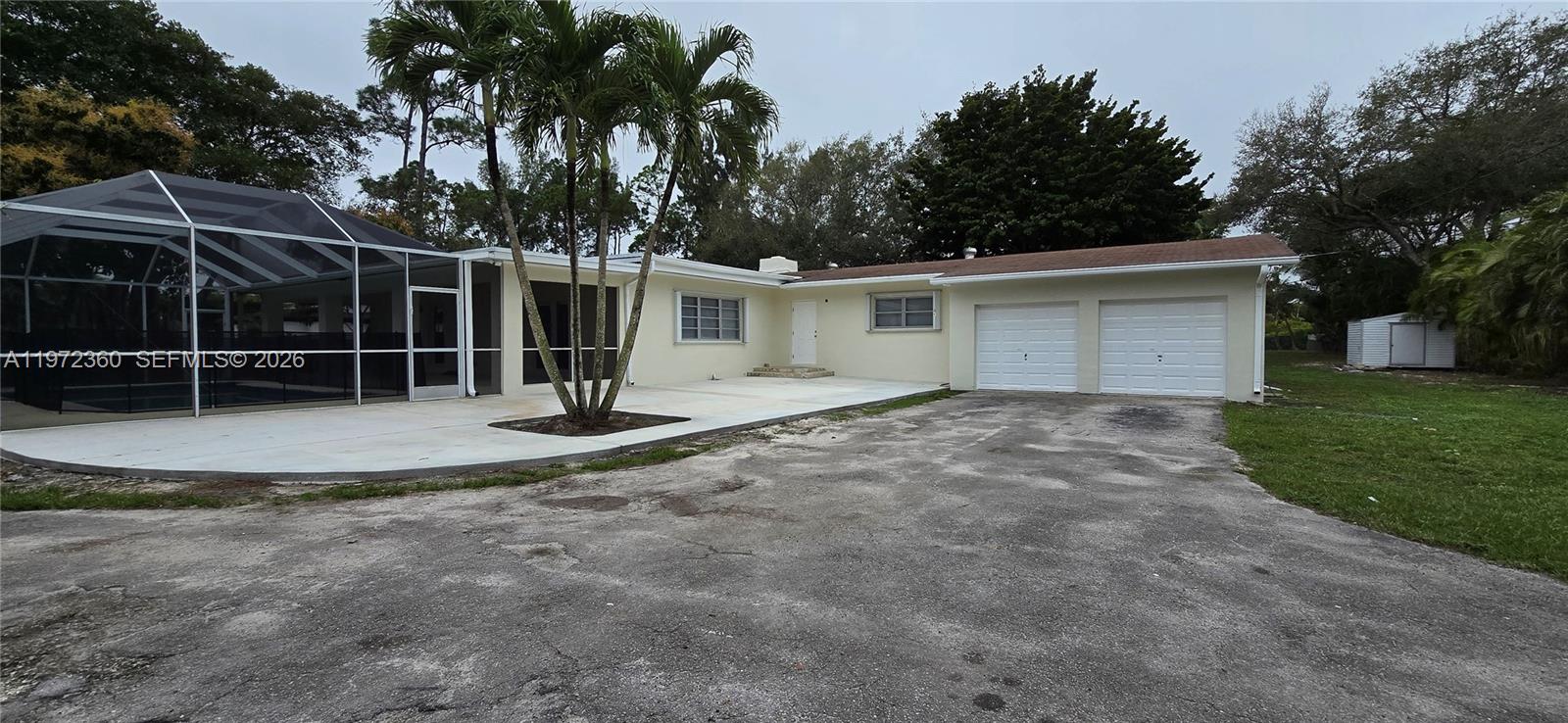 A single-story house features a two-car garage, a screened pool enclosure, and palm trees — 6500 SW 82nd Ave, Miami FL 33143, MIAMI, FL