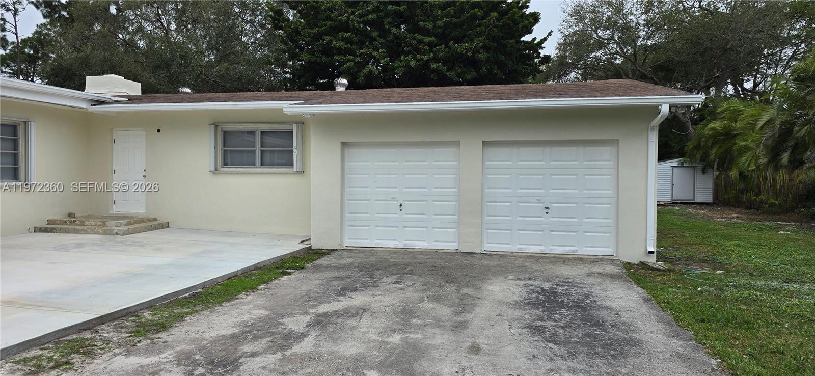 The exterior of a house features a two-car garage, a concrete driveway, and a door — 6500 SW 82nd Ave, Miami FL 33143, MIAMI, FL