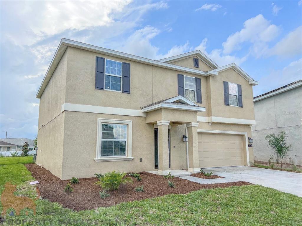 A two-story, beige stucco suburban house with a two-car garage and dark shutters — 5030 FOUR STRAND COURT, ST CLOUD, FL