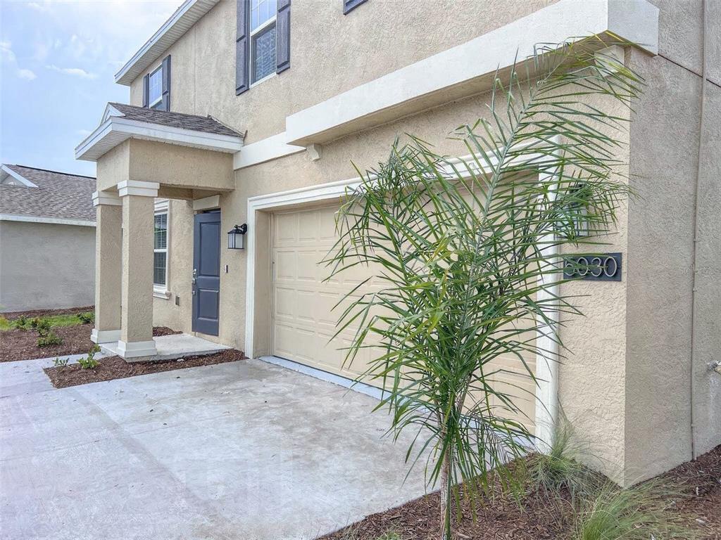 A beige two-story house exterior features a single-car garage, a front door, and a palm tree — 5030 FOUR STRAND COURT, ST CLOUD, FL
