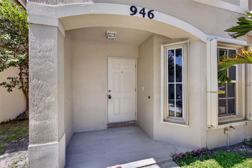 A covered entryway features a white front door, a tall window, and tiled flooring — 946 SUMMIT LAKE DRIVE, WEST PALM BEACH, FL