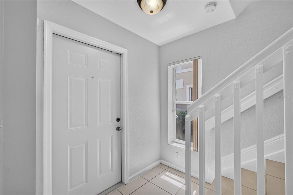 An entryway features a white front door, tiled flooring, and a white staircase railing — 946 SUMMIT LAKE DRIVE, WEST PALM BEACH, FL